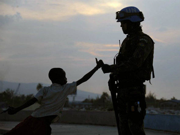 Soldado brasileiro da Minustah cumprimenta menino haitiano em favela de Porto Príncipe (Foto: AFP / Vanderlei Almeida)