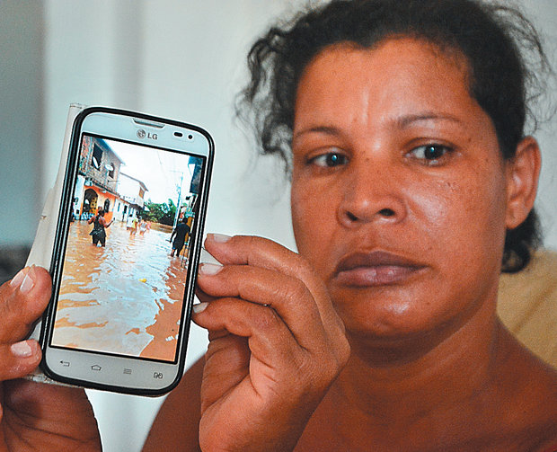 A auxiliar de dentista Ednice mostra foto de inundação, com sua casa ao fundo em Santo Amaro (Foto: Mauro Akin Nassor)