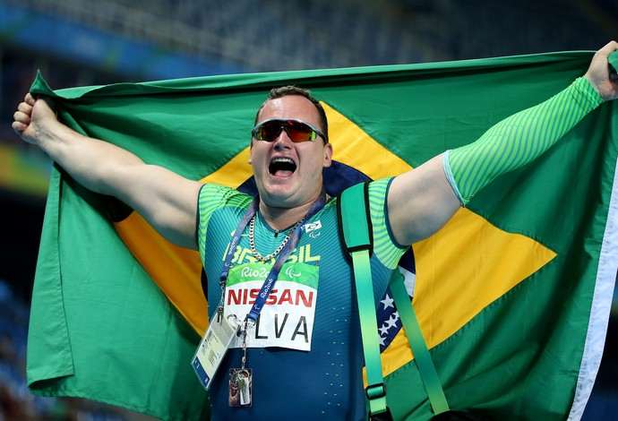 Descrição da imagem: Alessandro da Silva vibra com a bandeira brasileira na pista (Foto: Fernando Maia/MPIX/CPB)