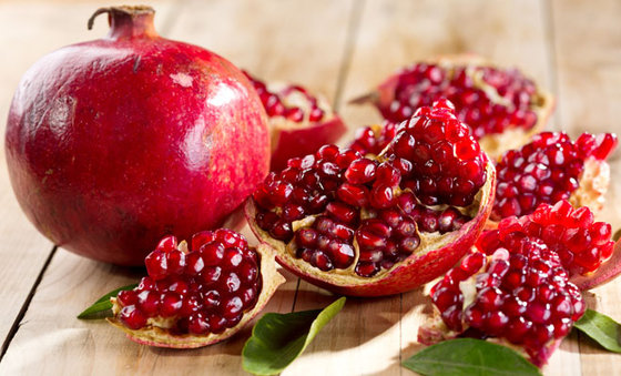 pomegranate with leafs on wooden table