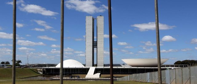 Manifestante solitário se amarra a cruz em frente ao Congresso