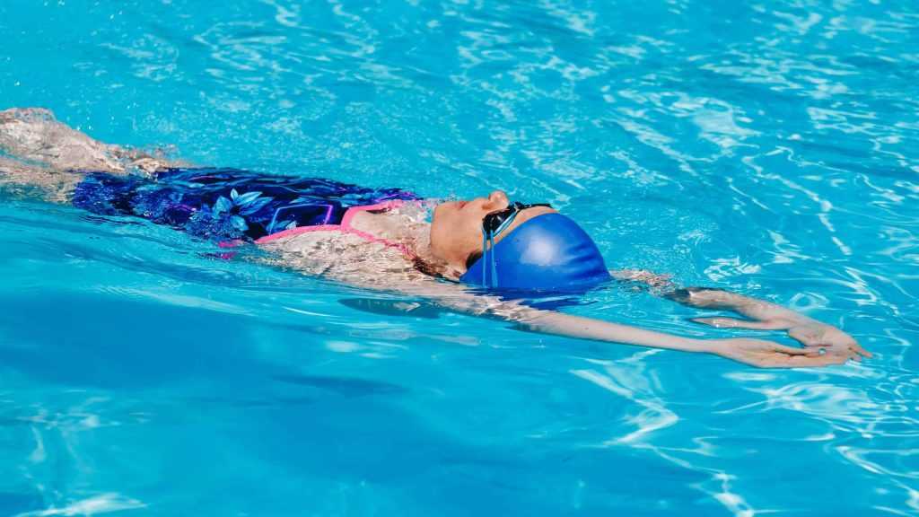 Mulher esportiva em óculos nadando de volta na piscina